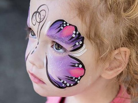 A young child in a purple butterfly face-paint